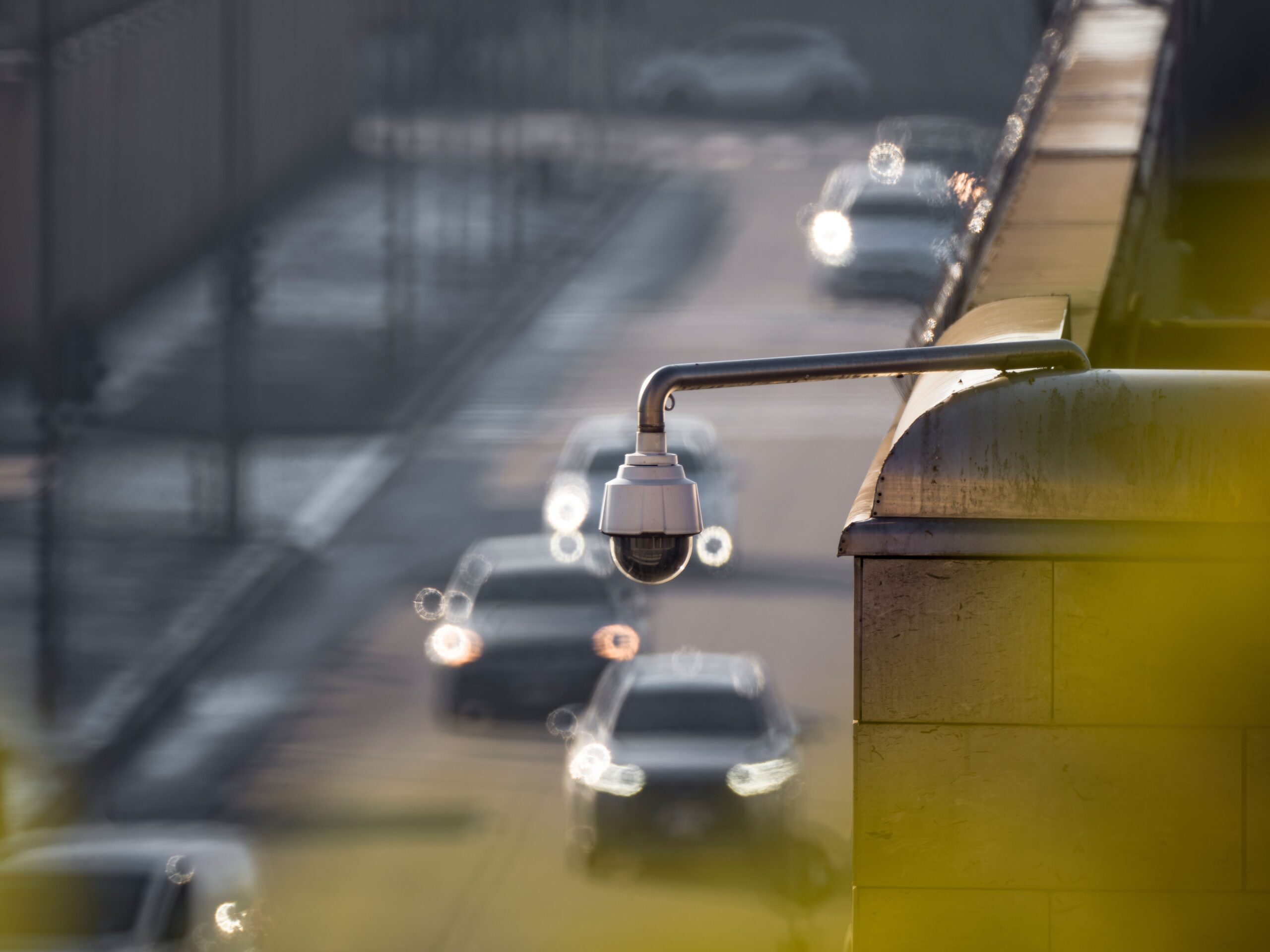 道路を見下ろす位置に取り付けられた監視カメラと、行き交う車