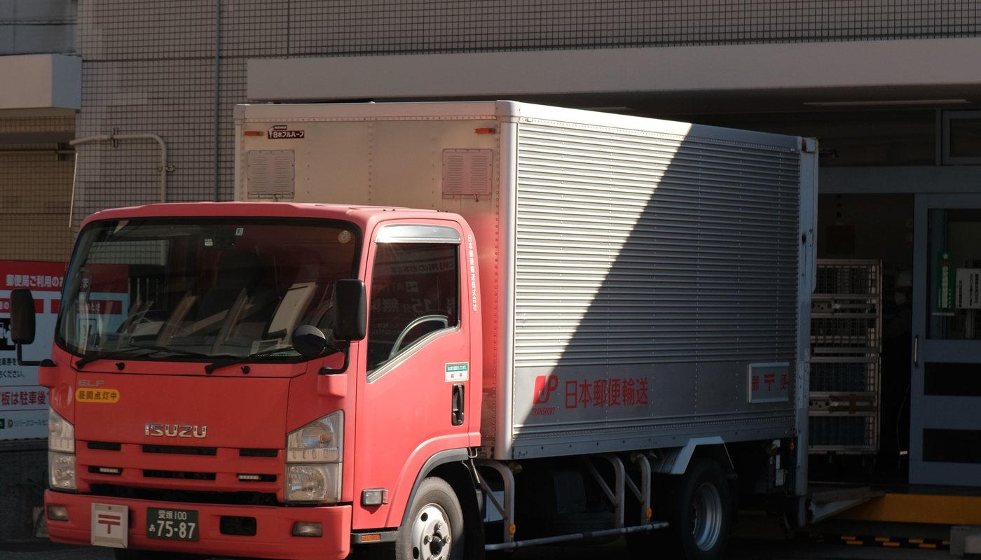 荷台の付いた小型トラックが、建物の前に停まっている