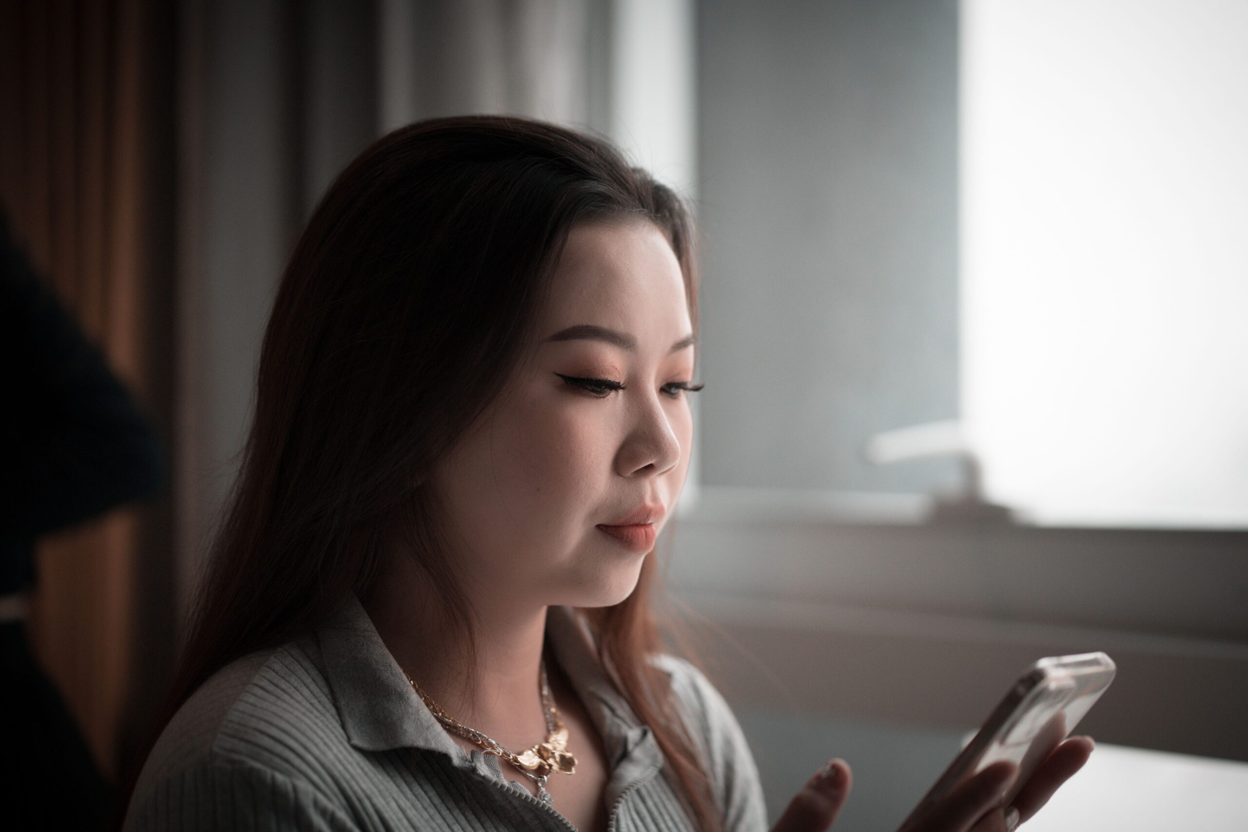 室内でスマートフォンを見る女性